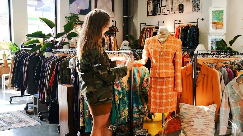 Probando tu marca de moda con pop-ups locales y retroalimentación del mercado Pequeño puesto de ropa de marca en un mercado local con letreros hechos a mano